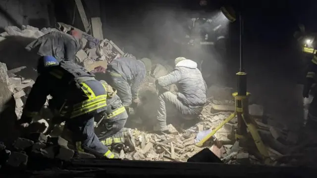 Rescuers searching rubble in the dark for survivors and bodies after a rocket attack