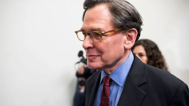 Sidney Blumenthal is followed by camera crews through a corridor in Congress