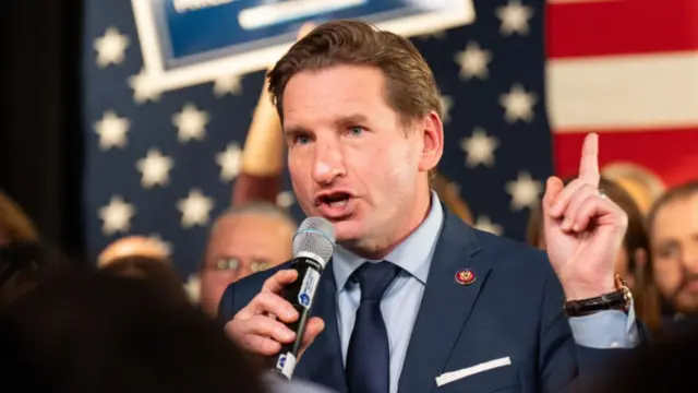 Dean Phillips holds a microphone at an event in New Hampshire