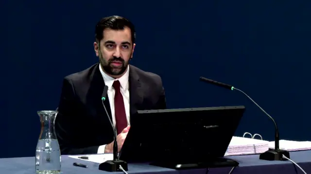 Humza Yousaf sat in front of a computer