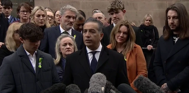 Grace O'Malley-Kumar's father Dr Sanjoy Kumar speaking to press with family members of other victims standing behind him