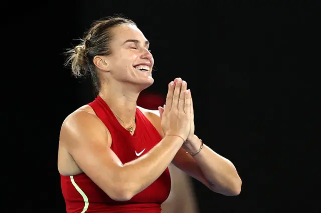 Aryna Sabalenka closes her eyes and smiles and puts her hand together