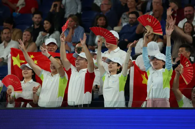 Fans hold Chinese flags and Chinese flag decorated hand fans