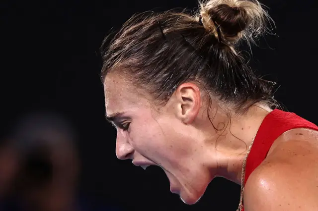 Aryna Sabalenka screams in relief looking down at the ground