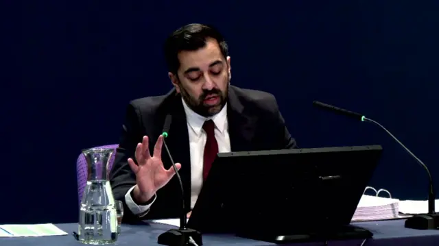 Humza Yousaf sat in front of a computer