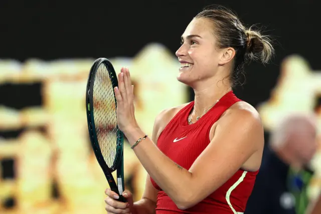 Aryna Sabalenka claps her racquet in celebration