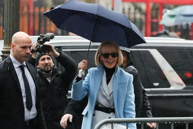 E Jean Carroll arrives at court holding an umbrella.