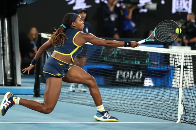 Coco Gauff stabs a volley at the net