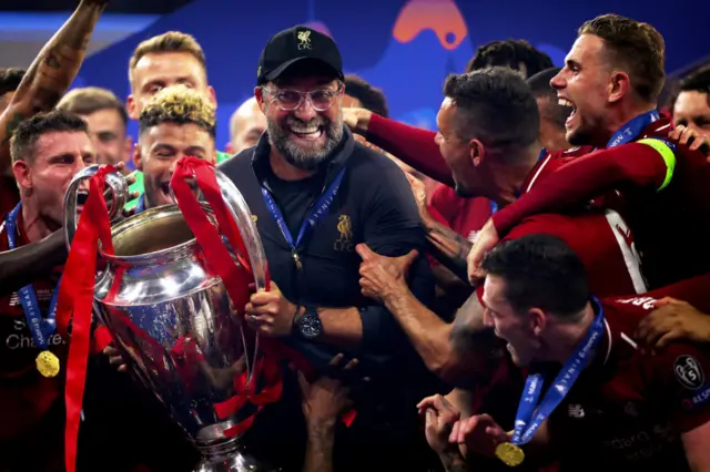 Jurgen Klopp holds the Champions League trophy surrounded by Liverpool players