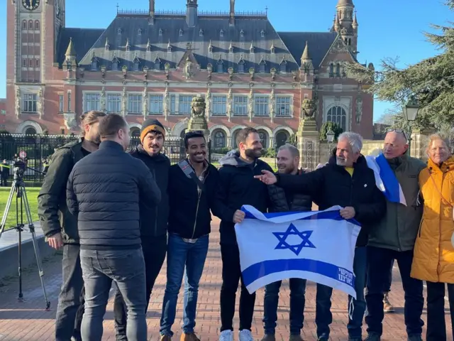 Group of supporters holding Israel flag in front of ICJ