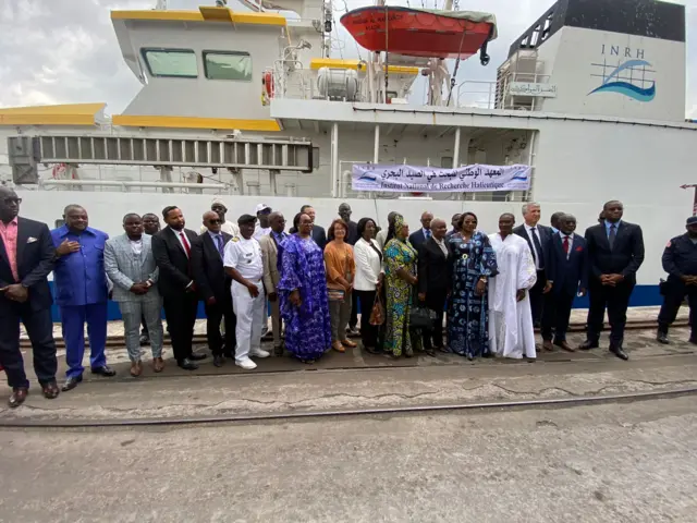 A group of people in front of a boat