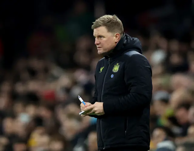 Eddie Howe writes notes while stood in his technical area.