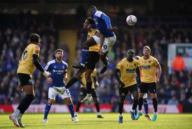 Players jump into an aerial duel in midfield.