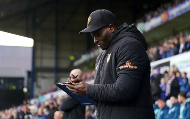 George Elokobi writes notes on the touchline.