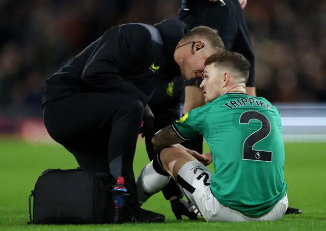 Trippier is tended to by medics while sat on the floor.