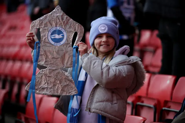 A young Brighton fan holds up a tinfoil cup.