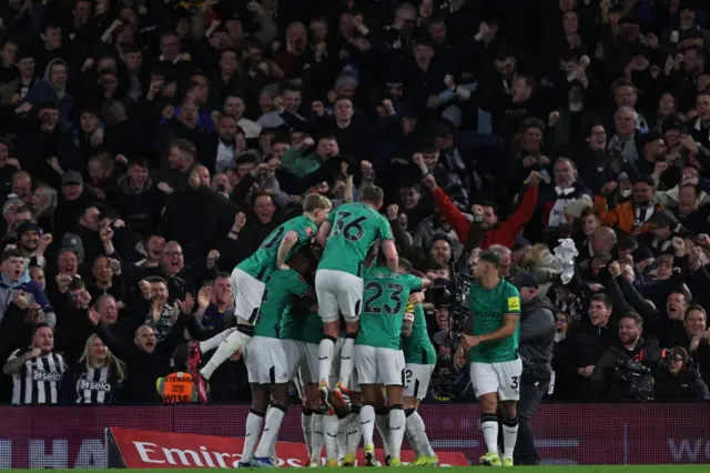 Newcastle players celebrate in front of the away fans.