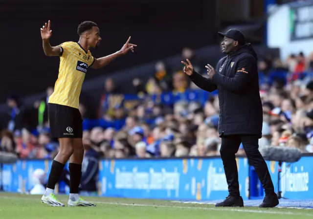 Elokobi gives instructions to one of his players on the sideline.