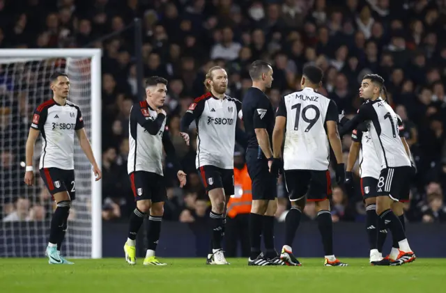 Fulham players contest the Newcastle opener with the referee.