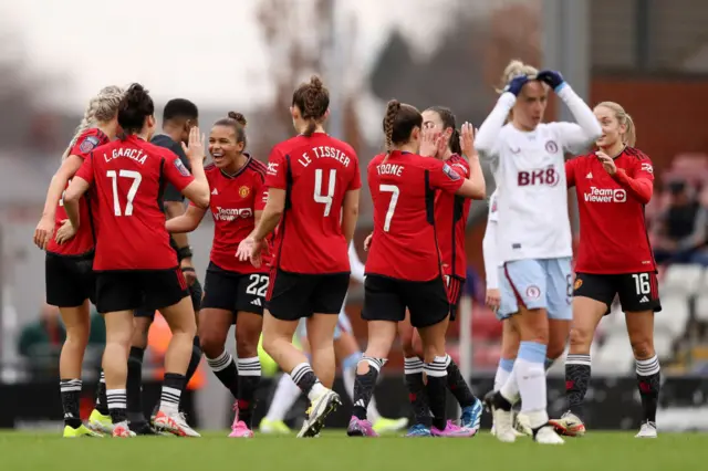 United celebrate Parris' goal as Nobbs adjusts her headband in the foreground.