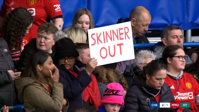 A fan holds a placard reading 'Skinner out'