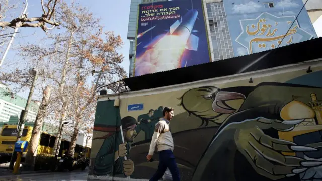 A man walks past a billboard showing missiles in flight