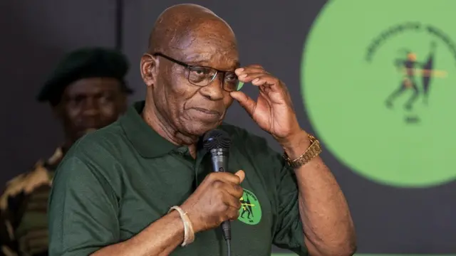 Former South Africa president Jacob Zuma holding a microphone at a press conference