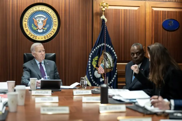 US President Joe Biden and US Defence Secretary Lloyd Austin sit around a table in the situation room and listen to a woman speak