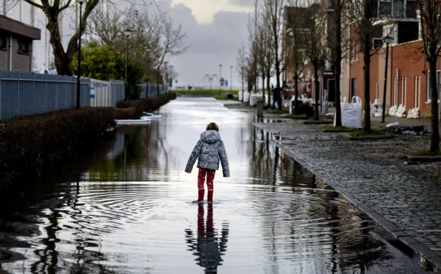 A child stands in a flooded street near the Markermeer after the first storm of this year, which was named Henk, in Hoorn