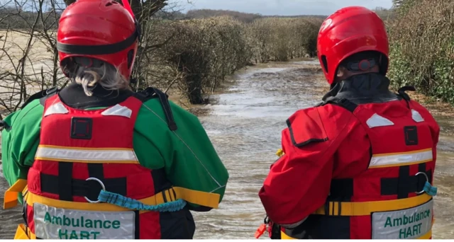 Ambulance crew look at flood