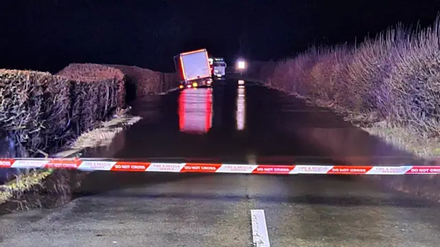 A lorry at night in a ditch on the side of the road