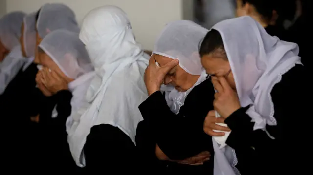 Druze women, some with their heads in their hands and others crying, at the funeral of the killed soldier