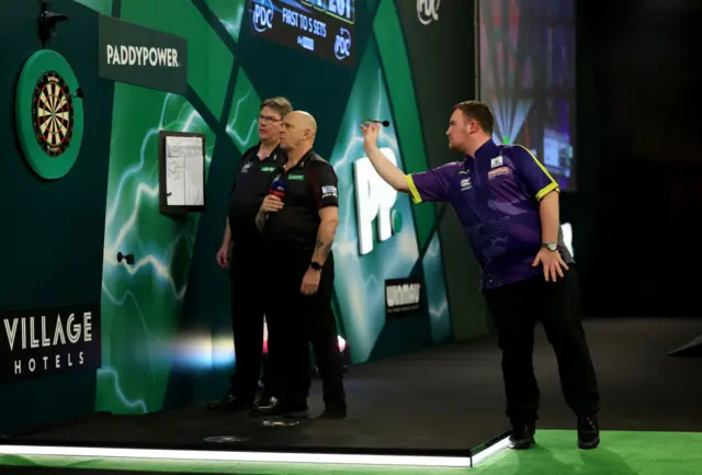 Luke Littler plays darts as referee Russ Bray watches on