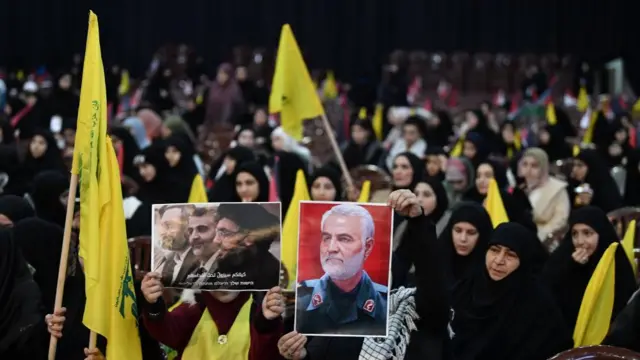 A woman holds the photo of top late Iranian commander Qasem Soleimani (R), as people gather to watch a televised speech by Hezbollah secretary general Hassan Nasrallah