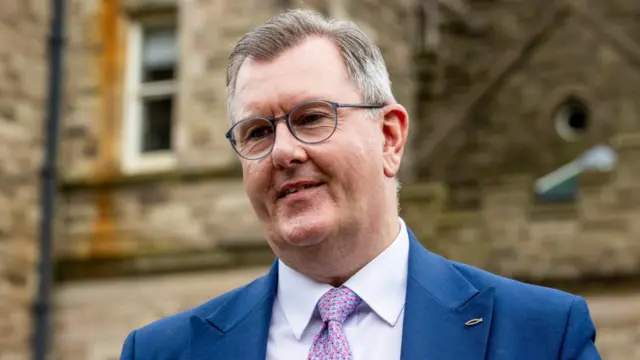 Sir Jeffrey Donaldson wearing a suit, standing outside a building