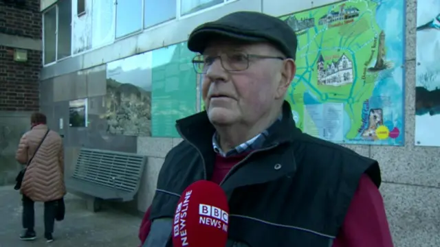 A man standing in a street being interviewed