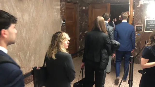 A queue of people outside the door of an ornate building