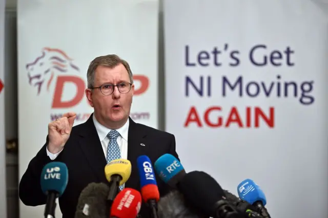 Sir Jeffrey Donaldson stands in front of a cluster of microphones as he addresses the media.