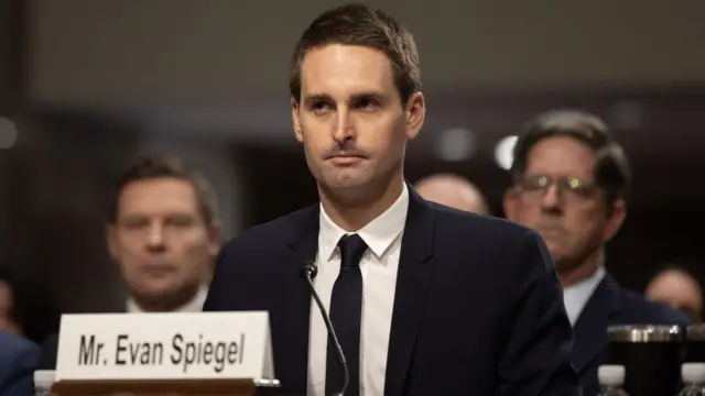 Spiegel sits at the hearing