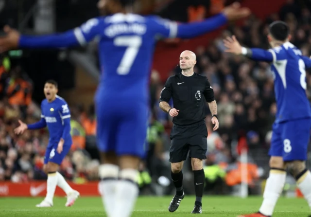 Referee Paul Tierney reacts as Chelsea players remonstrate