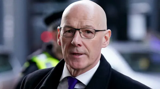 Former Deputy FM john Swinney arrives at the Covid inquiry wearing a black suit and blue tie