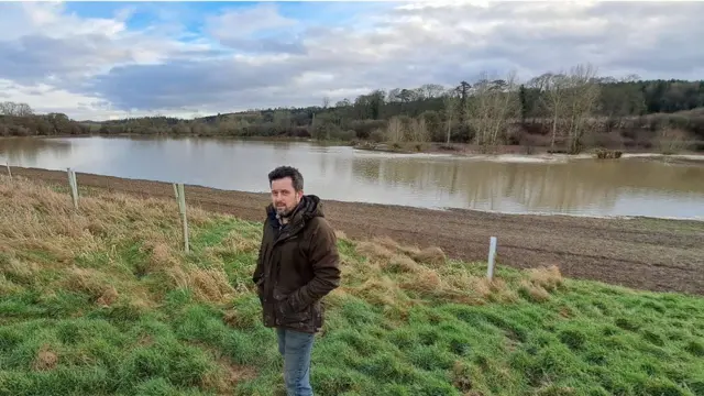 Ollie Stobo stood next to flood water on his farm