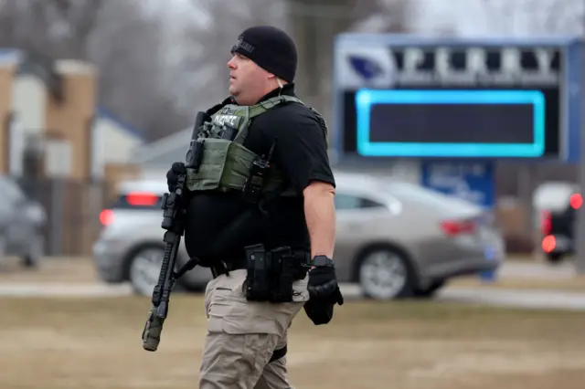 An armed sherrif walks outside Perry High School