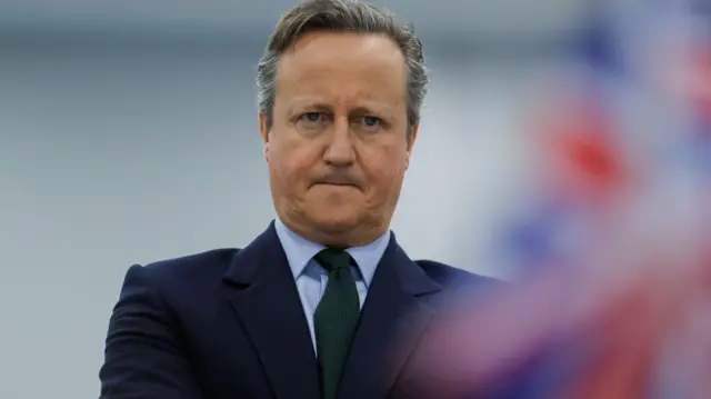 UK Foreign Secretary David Cameron stands with his arms crossed