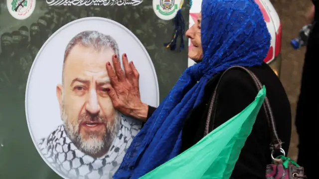 A woman touches a picture of deputy head of Hamas, Saleh al-Arouri,