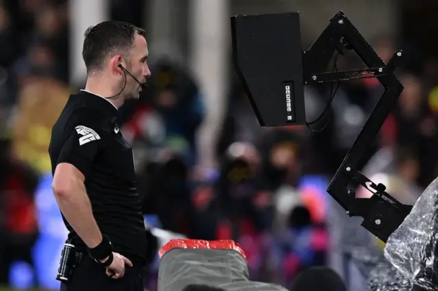 Referee checks the pitchside monitor.