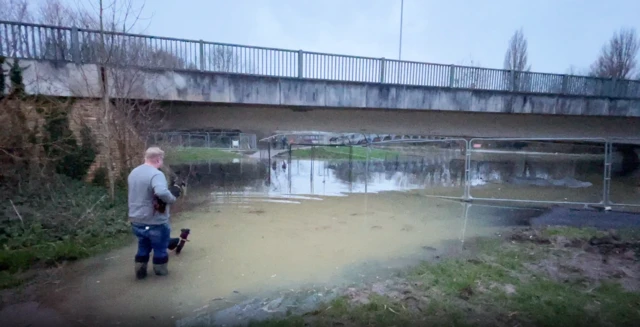 A man with two dogs standing in flood water