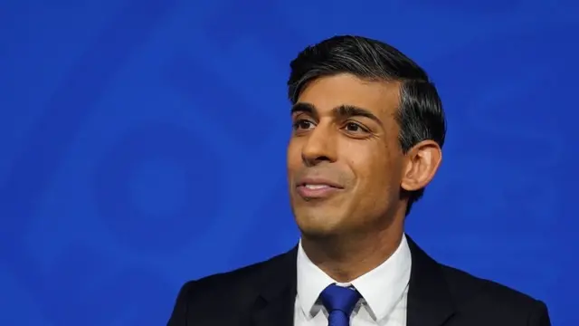 Rishi Sunak in front of a blue background