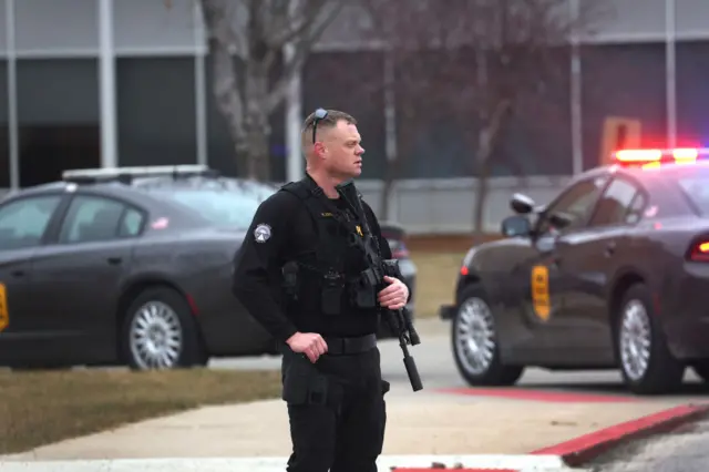 A police officer stands guard outside the Perry Middle School and High School complex