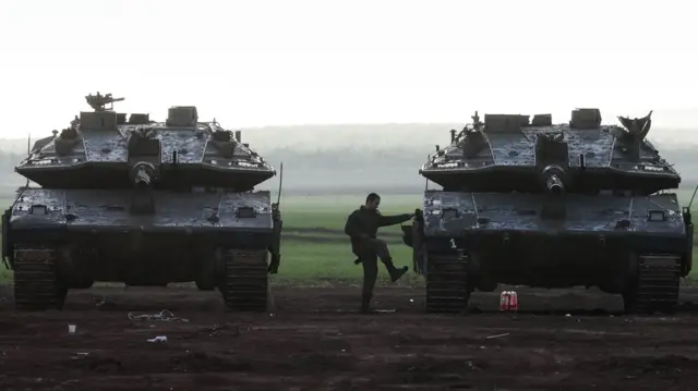 An Israeli soldier climbs aboard a tank near the border with Gaza